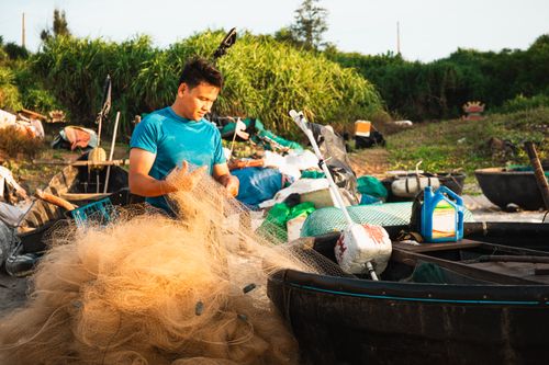 Free A fisherman mends his nets on a sunny day in Quảng Trị, Vietnam. Stock Photo