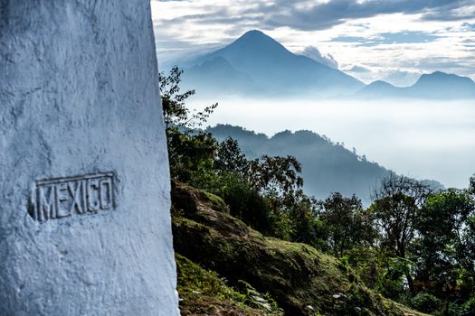 A stunning view from San Marcos, Guatemala, featuring misty mountains and a Mexico boundary marker.