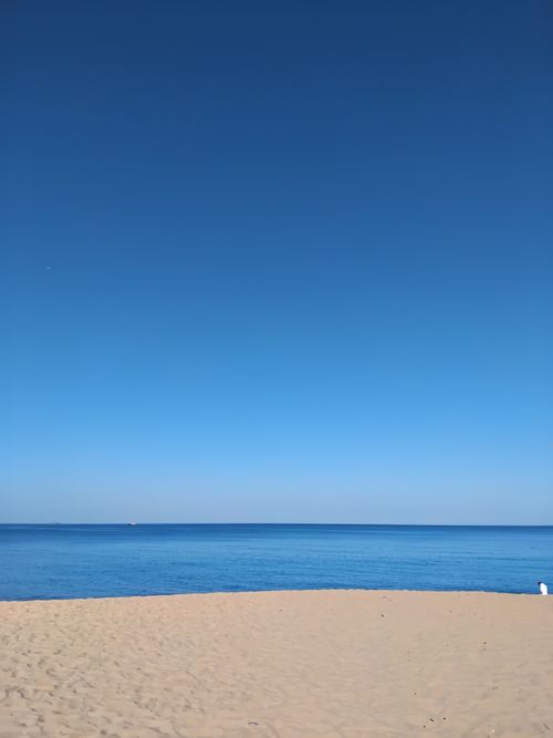 Free A tranquil beach scene with clear blue skies, ideal for travel and relaxation themes. Stock Photo