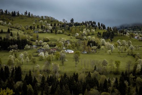 Free Breathtaking panorama of lush hills and scattered cottages under a cloudy sky. Stock Photo