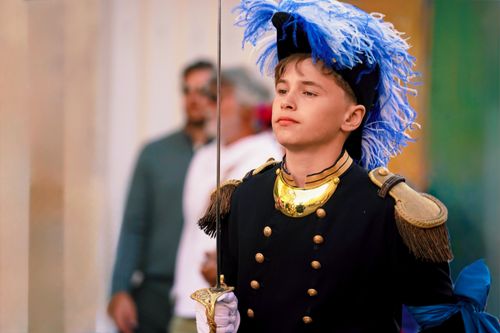Free Young boy dressed in ceremonial soldier uniform with feathered hat, holding a sword. Stock Photo