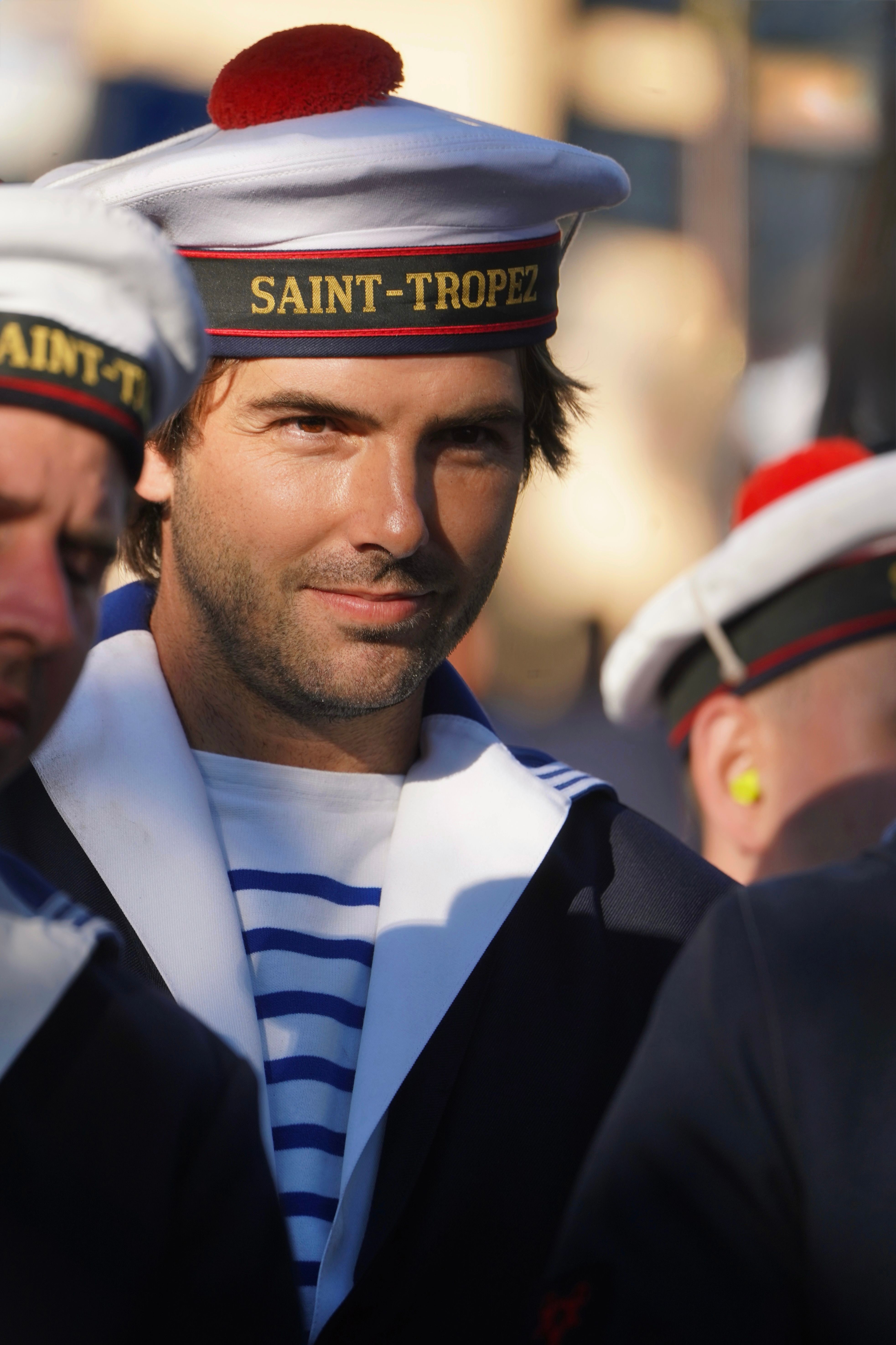 Portrait of a sailor wearing Saint-Tropez naval-themed uniform during a daytime event.
