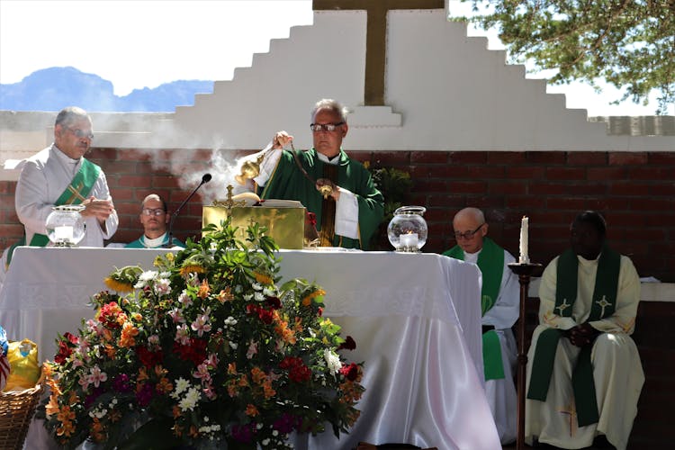 Senior Priest Waving Incense During Church Service Near Multiracial Coworkers