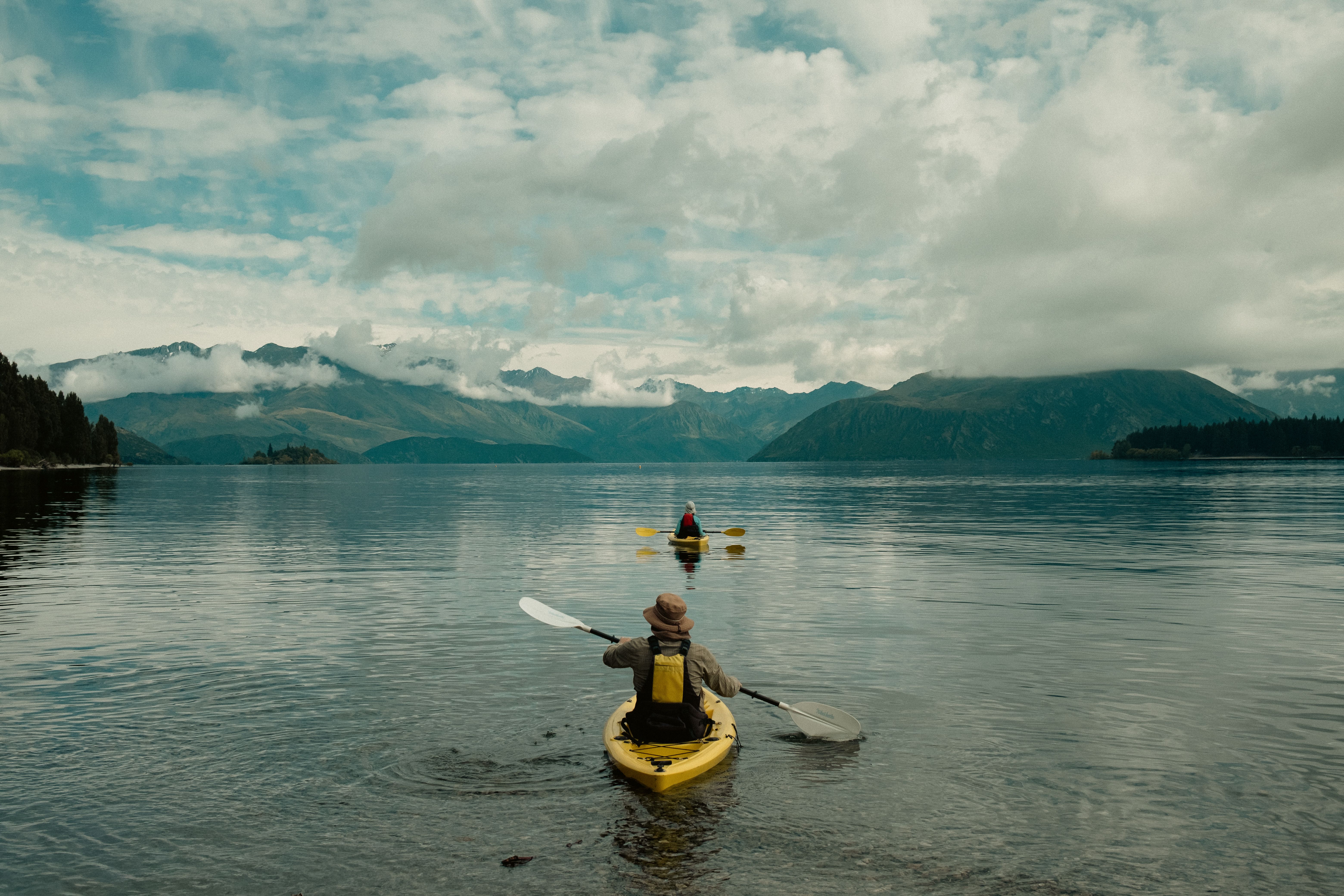 Two kayakers enjoy serene views on the picturesque Lake Wānaka in New Zealand.