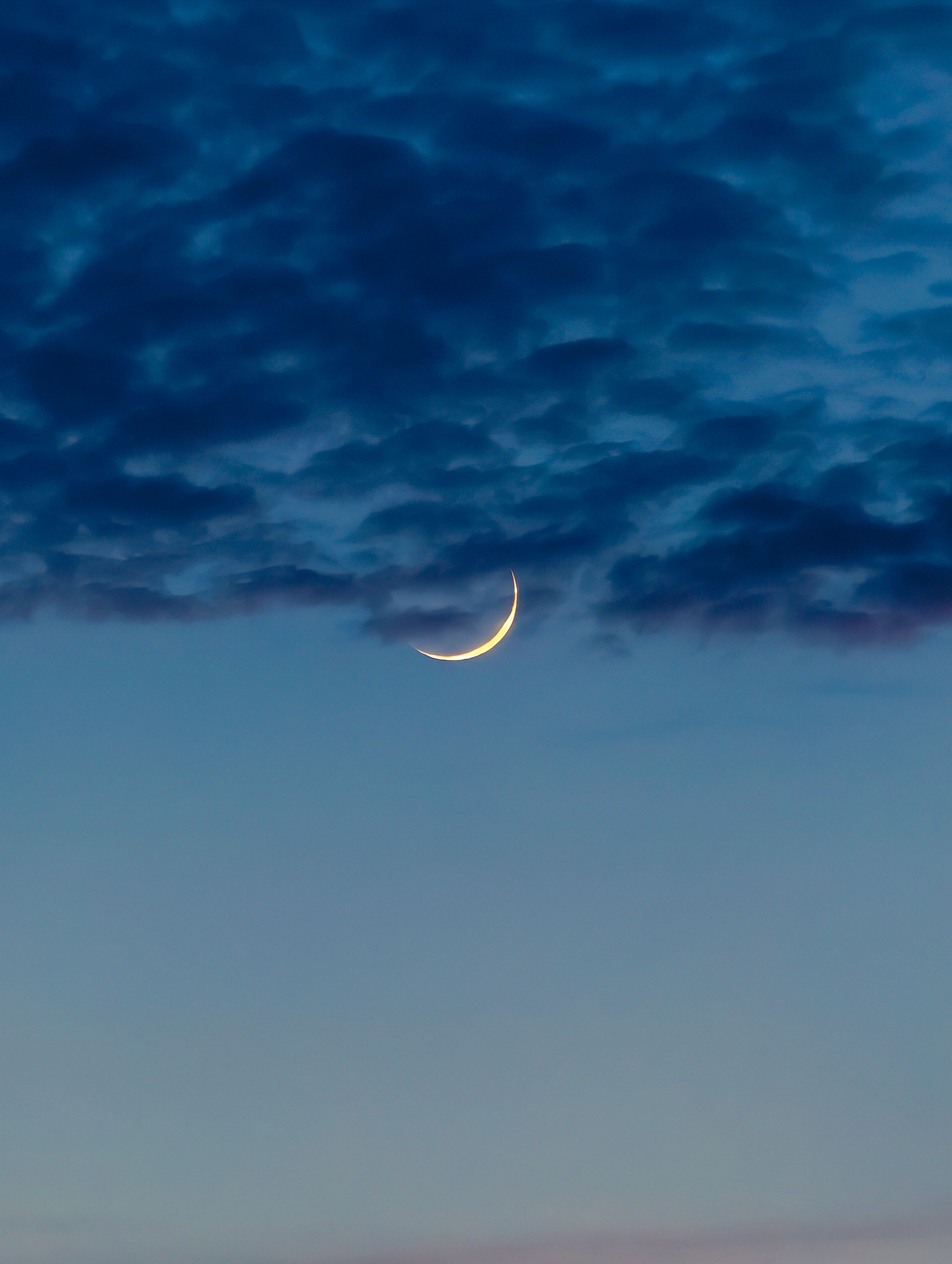 A serene crescent moon surrounded by twilight clouds in a clear sky, perfect for a calming or night-themed concept.