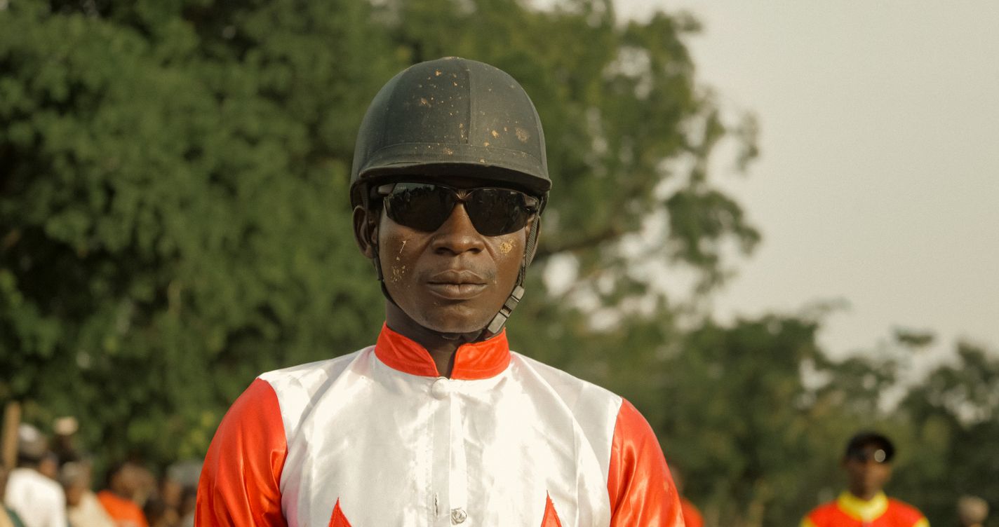 Portrait d'un jockey en tenue de course, casque à la main, avant une réunion hippique