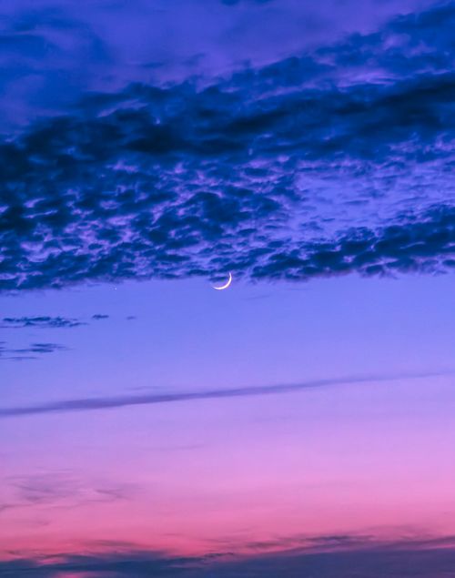 Free A stunning view of a crescent moon nestled in a vibrant twilight sky with hues of blue and purple. Stock Photo
