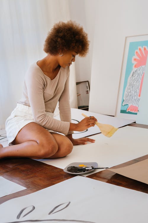 Gratis Foto De Mujer Sentada En El Suelo Sujetando Un Pincel Foto de stock