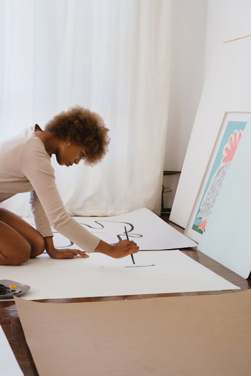 白いイラストボードに絵を描く女性の写真