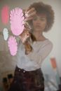 Concentrated black female artisan sticking paper flowers on glass wall