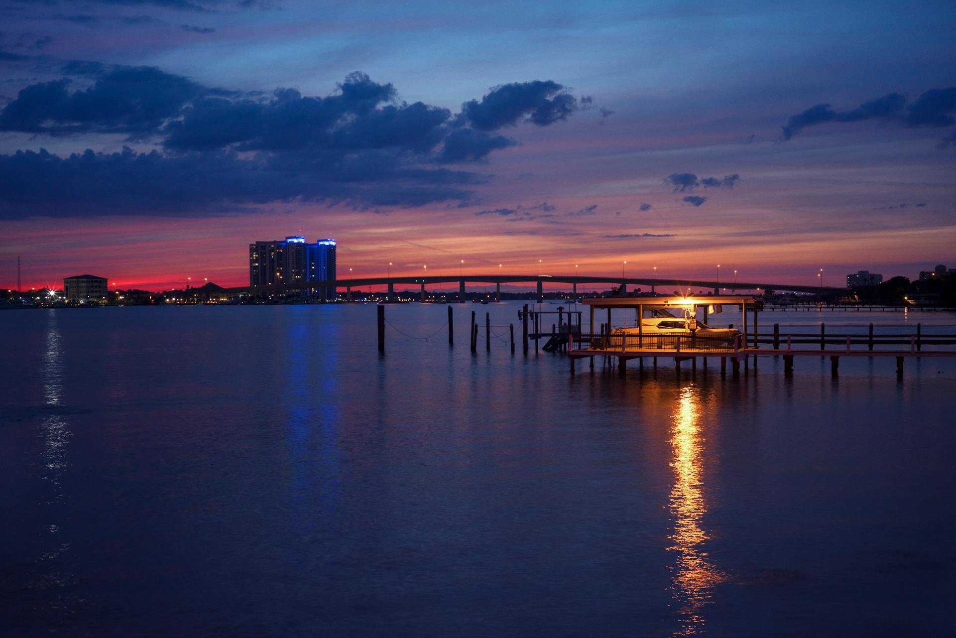 Peaceful shot of a harbor at twilight, featuring a pier and vibrant sunset reflections.