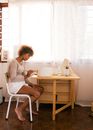 Side view of young barefoot female in casual outfit sitting at table and drawing on big handmade bowl in calm studio