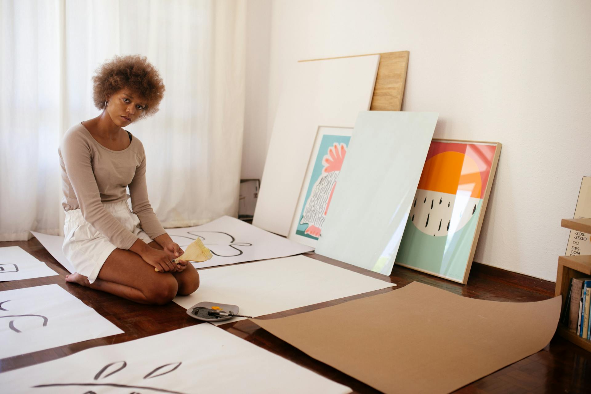 Young artist sitting on floor with artworks