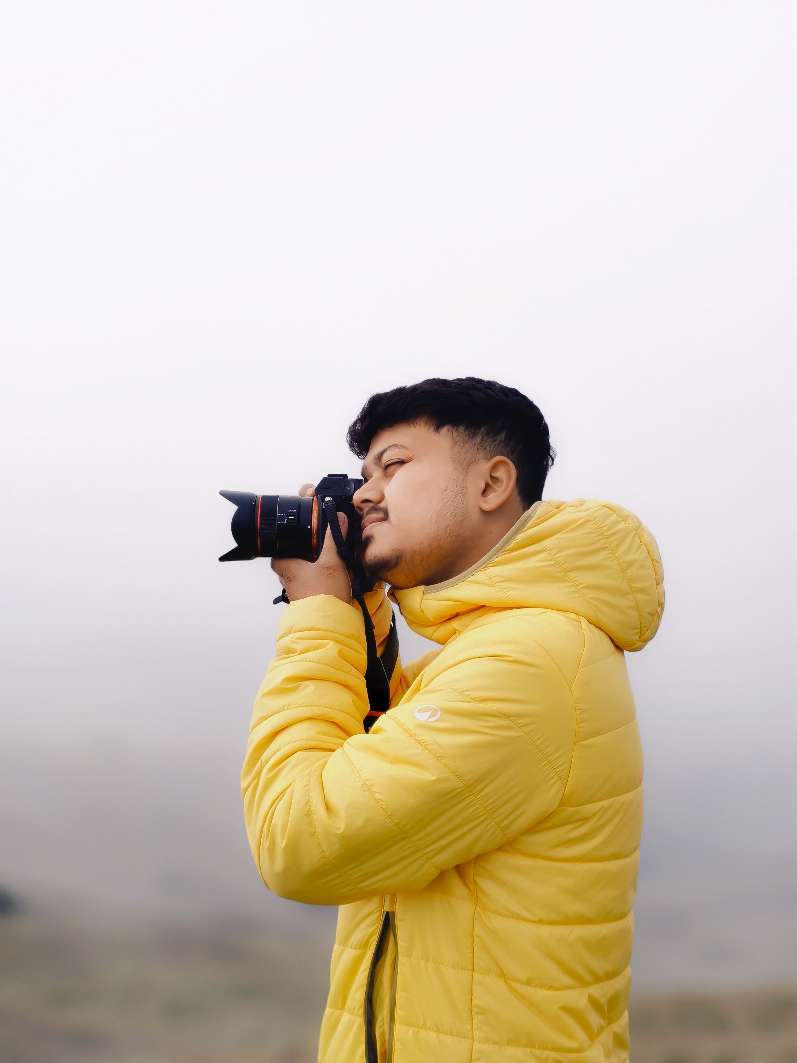 Photographer in a bright yellow jacket capturing a serene outdoor scene.