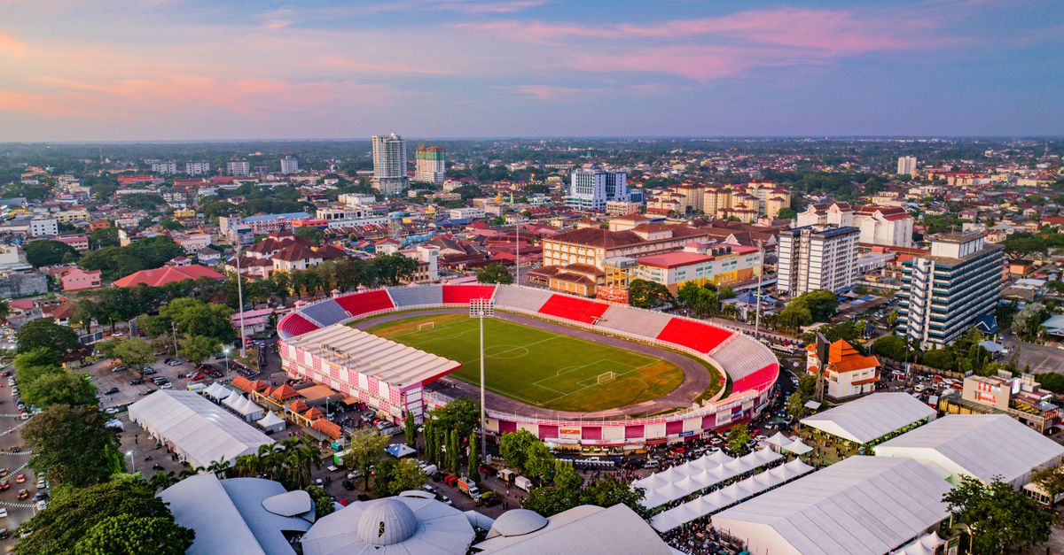 A stunning aerial view of a stadium in Kota Bharu, Malaysia at sunset surrounded by cityscape.