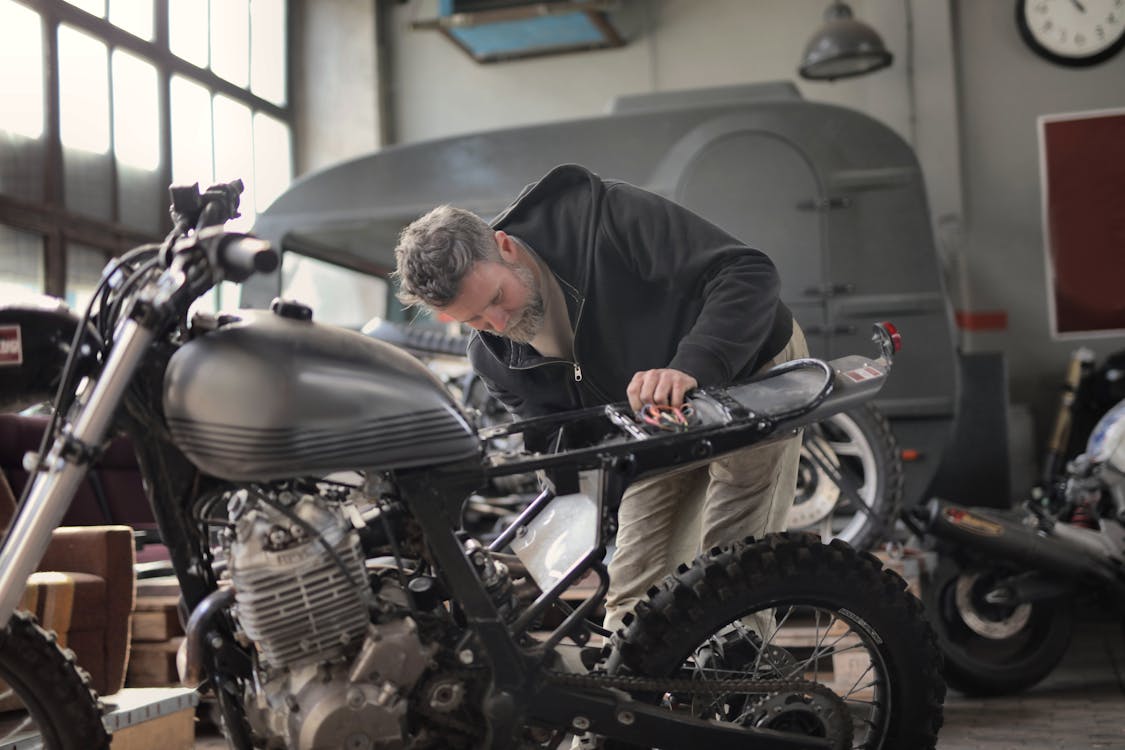 Free Man in Black Jacket Inspecting a Motorcycle Stock Photo