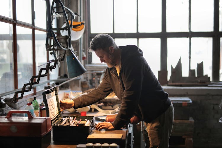 Man In Black Jacket Standing Near Table With Toolbox