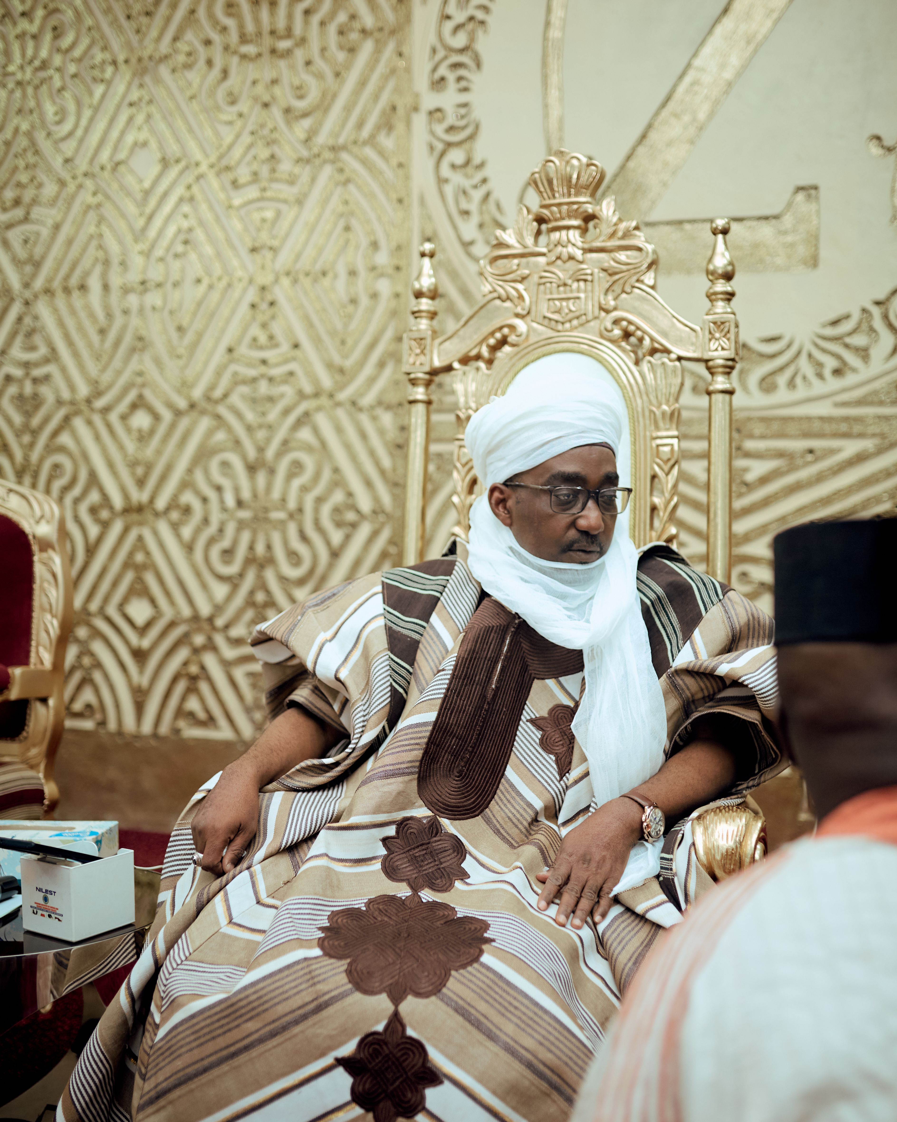 A traditional leader in ceremonial attire seated on a golden throne, showcasing cultural richness.