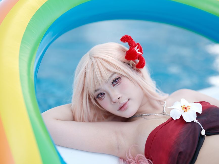 A cosplay model with vibrant makeup relaxes in a bright pool float.