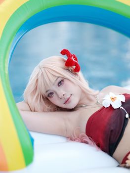 Woman lounging on an inflatable rainbow float, enjoying a sunny poolside moment.