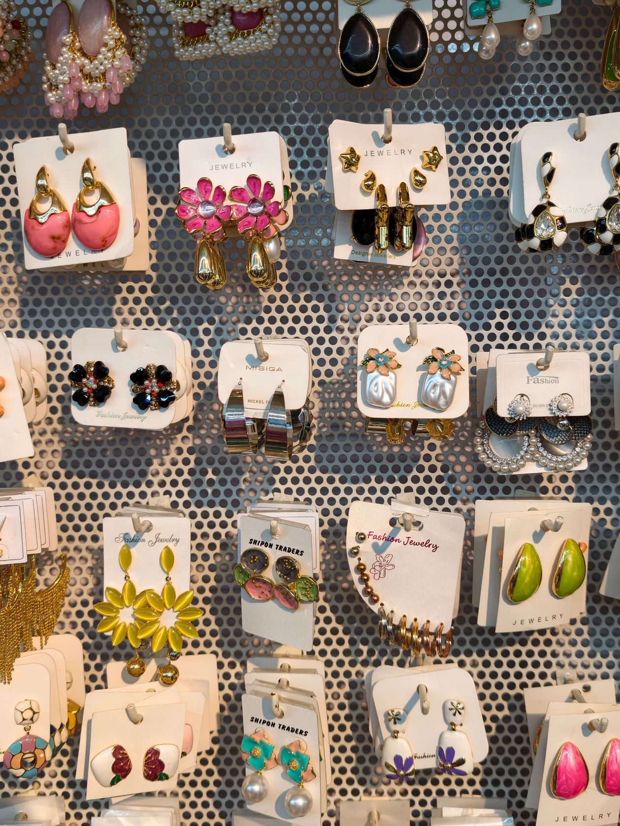 Brincos expostos em cartelas presas a um painel perfurado