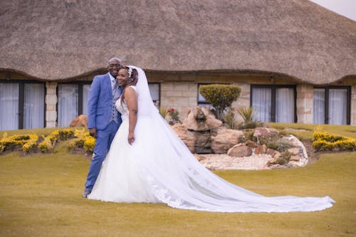 Photo of Married Couple Standing on Grass While Smiling