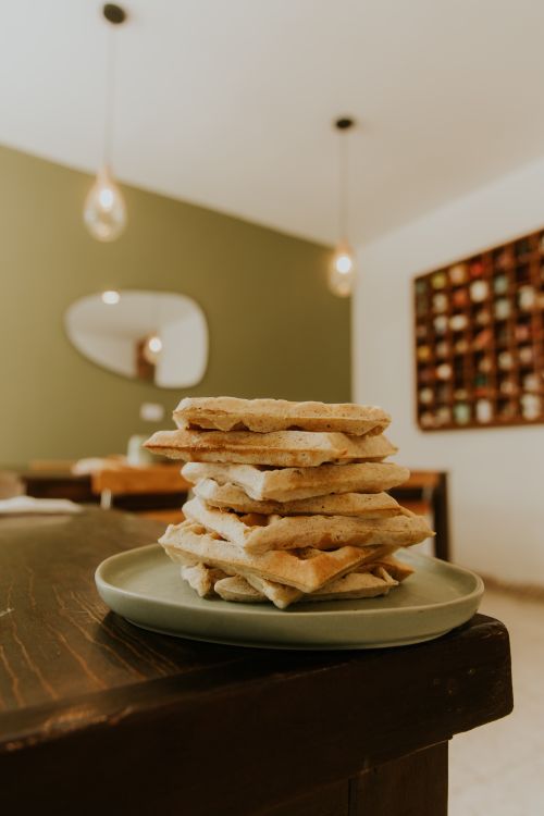Free A stack of fresh baked waffles served on a rustic plate indoors with warm lighting. Stock Photo