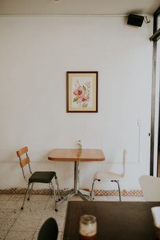 A cozy cafe corner with two chairs and floral art, perfect for a quiet moment.