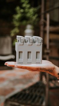A hand holding a sleek drone battery charger with three slots, outdoors.