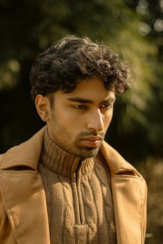 Portrait of a man in a brown coat outdoors with soft autumn light.