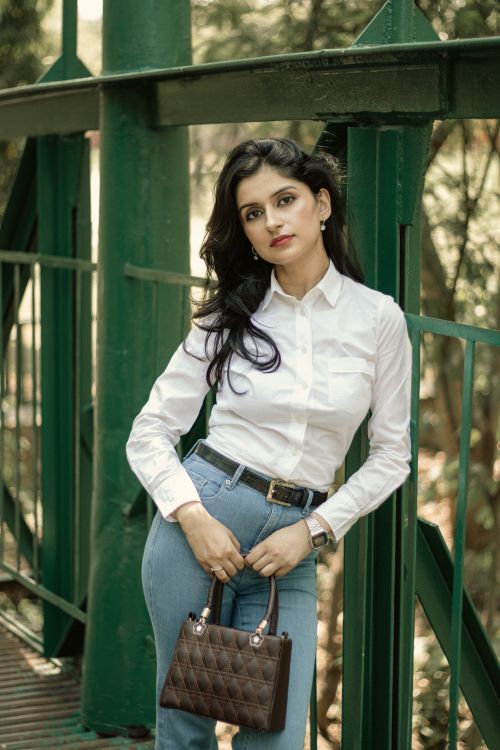 Free Stylish woman posing in white shirt and jeans on a sunny day outdoors. Stock Photo
