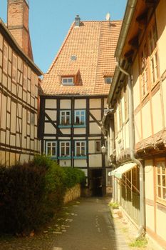 Discover the picturesque half-timbered architecture of Quedlinburg, Germany, in a sunlit alleyway.