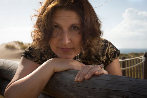 Free Portrait of a woman leaning on a wooden fence with a natural background, outdoors. Stock Photo