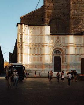 View of historical architecture and street life in Bologna, Italy, during summer.