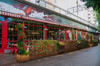 Charming outdoor dining area with vibrant florals and red accents, perfect for urban leisure.