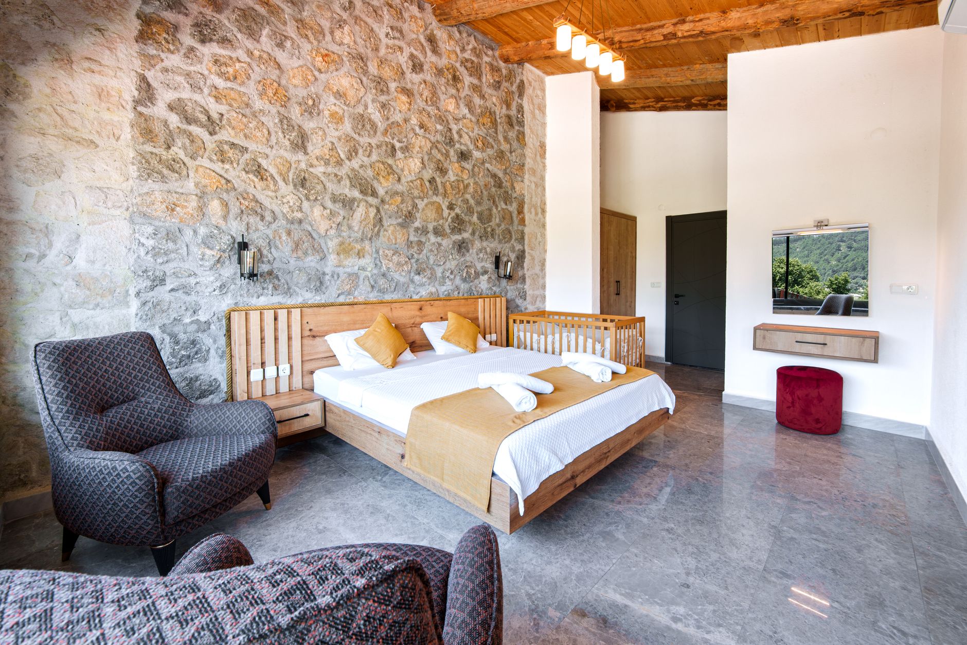 Spacious rustic bedroom with wood furniture and stone wall, ideal for relaxation and comfort.