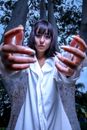Unemotional woman reaching arms near trees under blue sky