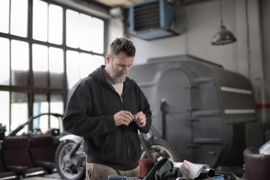Mechanic in a garage performing maintenance and repairs indoors.