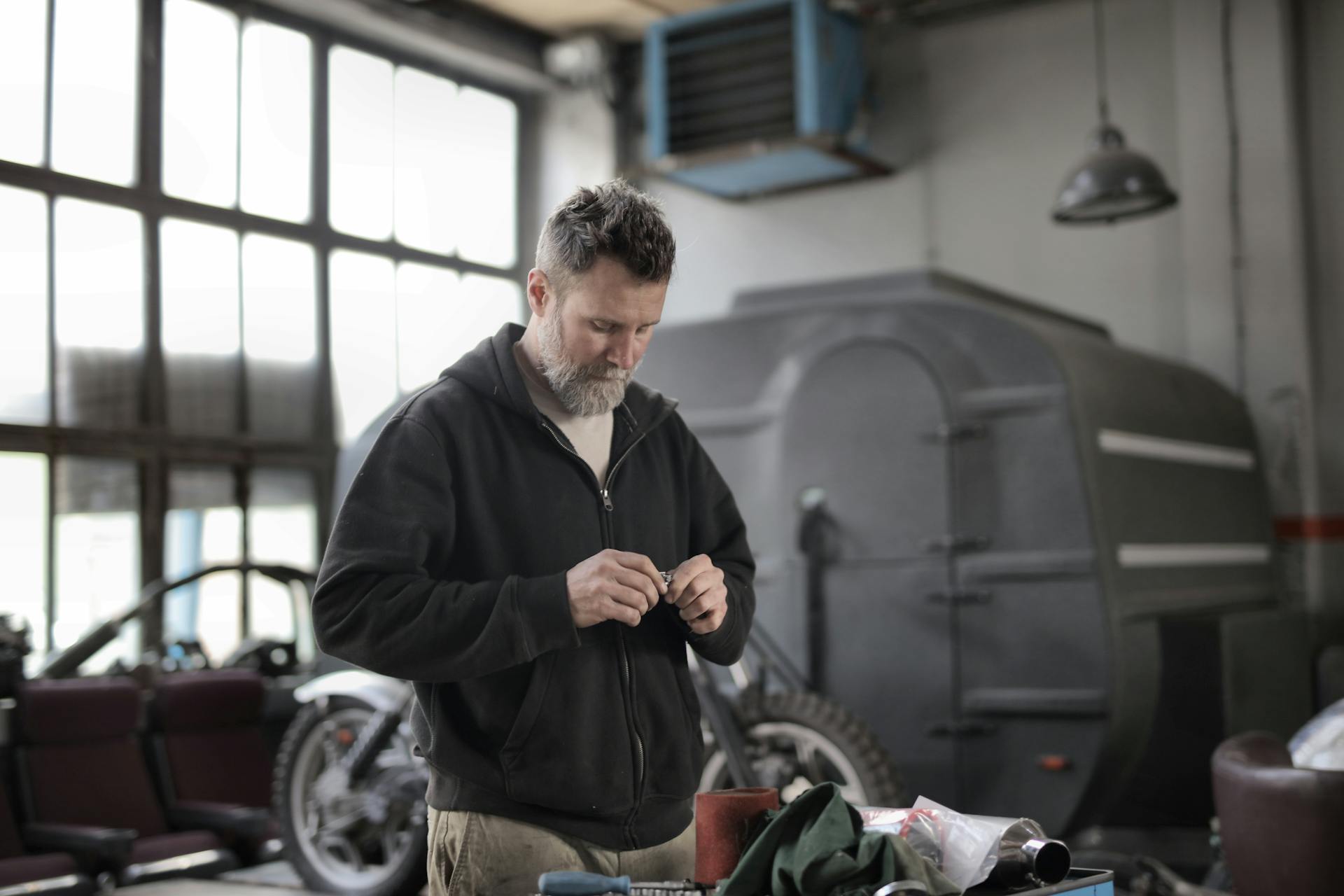 Mechanic in a garage performing maintenance and repairs indoors.