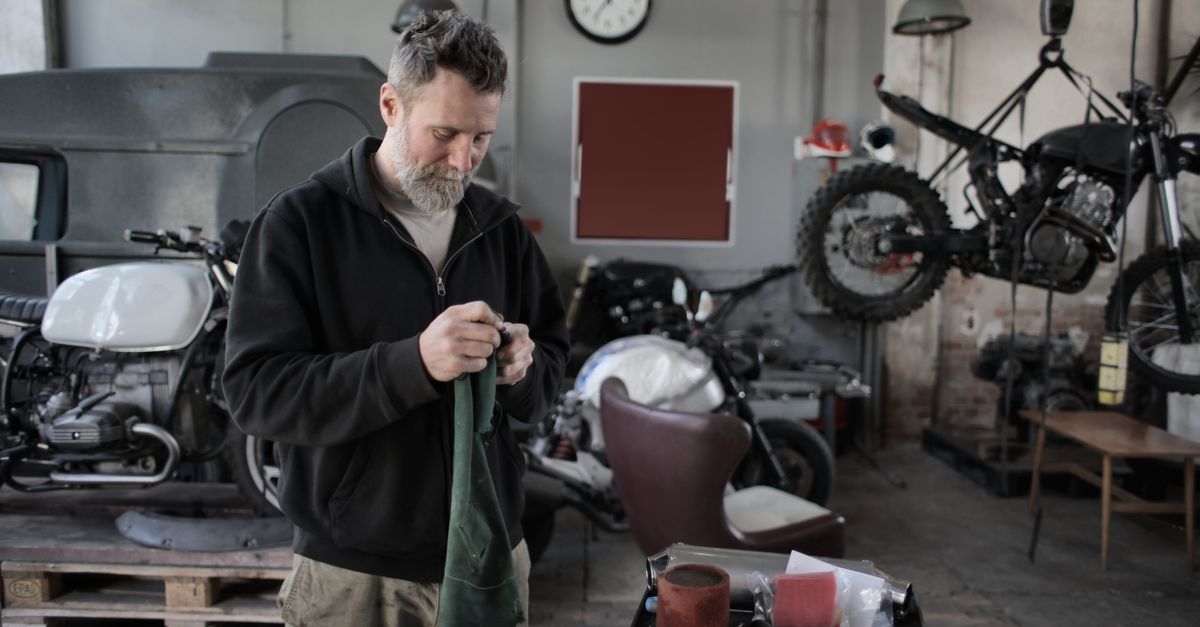 Mechanic focused on repairing motorcycles in an industrial workshop setting.
