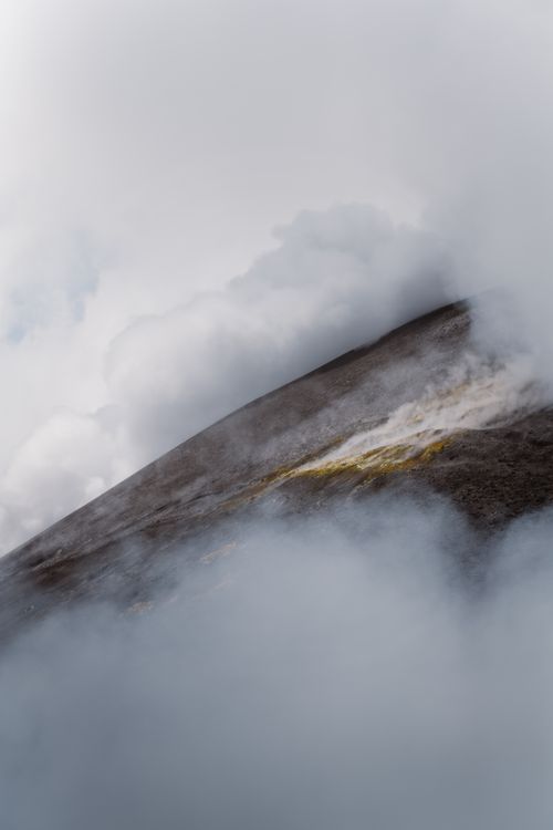 Free A serene view of a volcanic mountain enveloped in mist and steam clouds, creating a mystical atmosphere. Stock Photo