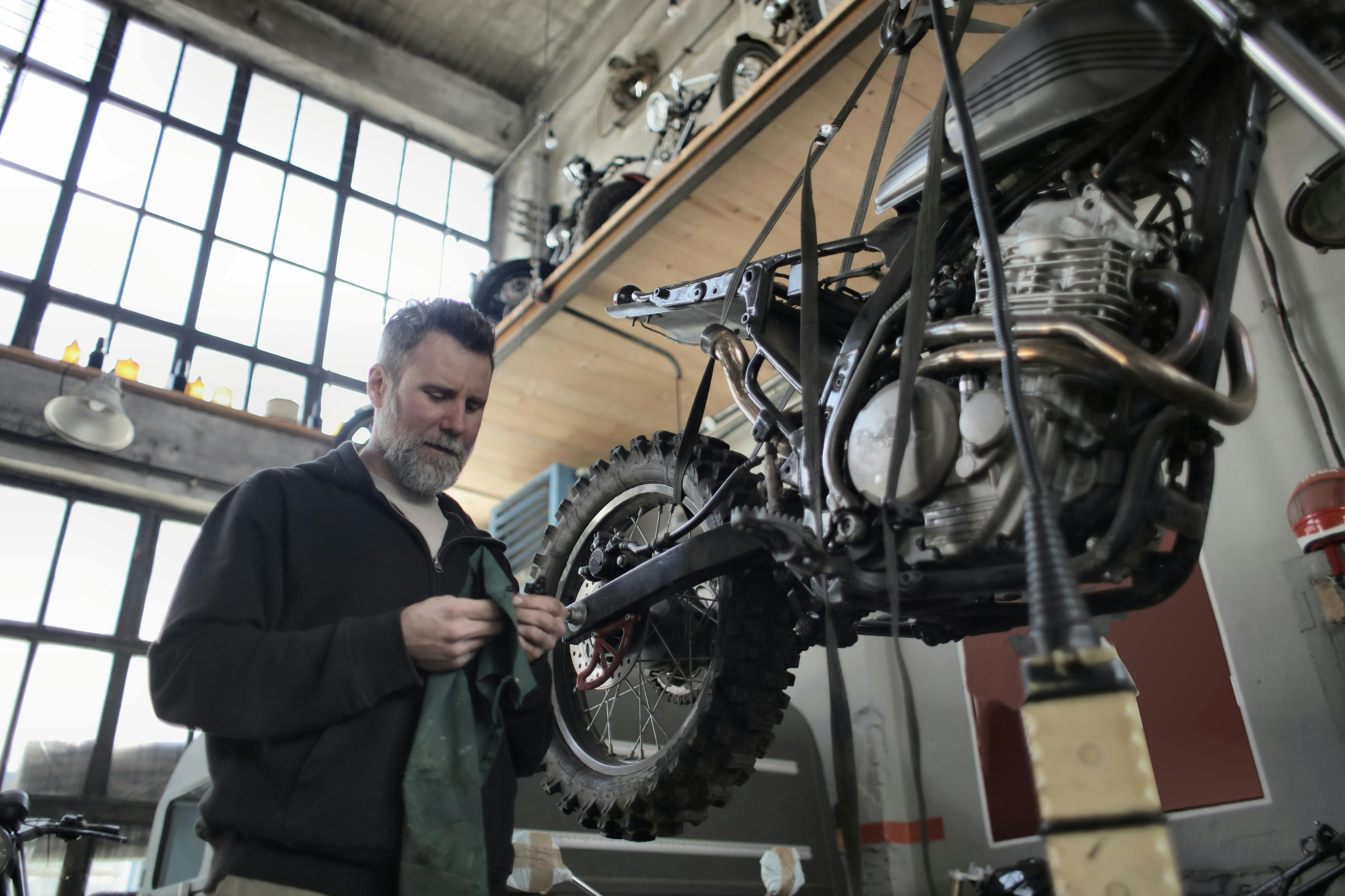 man in black jacket standing beside black motorcycle