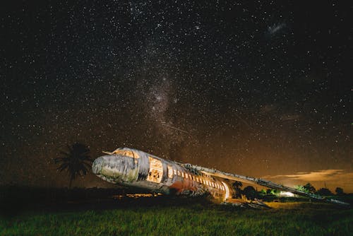 Старый раздавленный самолет горит на поле на закате