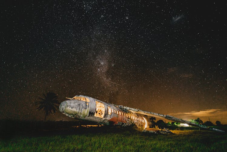 Old Crushed Aircraft Burning On Field At Sunset