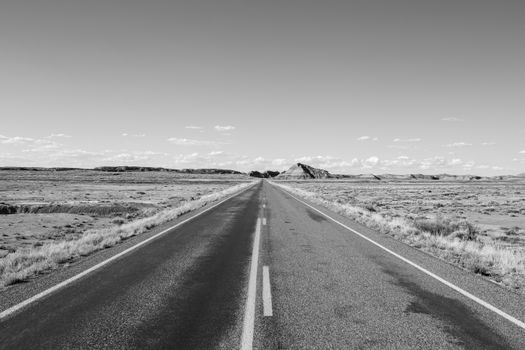 Monochrome view of an endless desert highway under a clear sky.