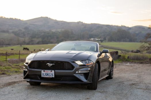 A sleek convertible car parked in a picturesque countryside setting during daytime.