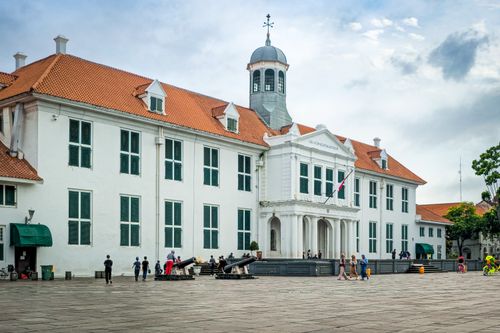 Free A scenic view of Jakarta's historic Fatahillah Museum featuring colonial architecture and lively public gathering. Stock Photo