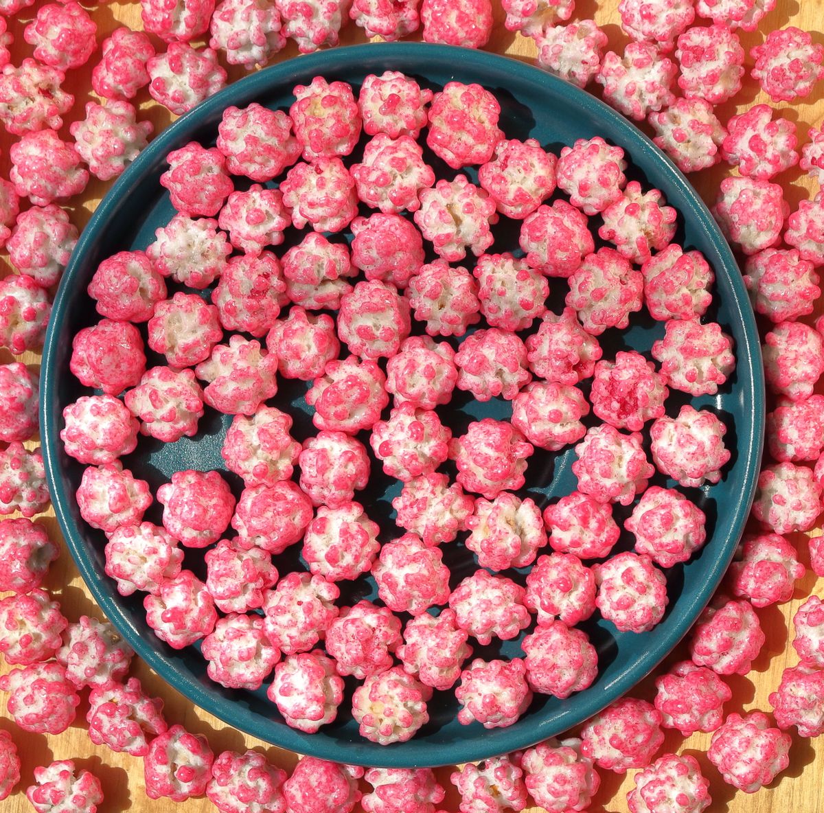 A top view of bright pink candy balls arranged neatly on a plate.