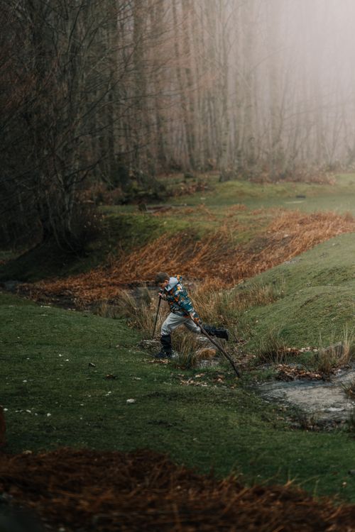 Free Elderly man with walking sticks treks through a misty forest, capturing nature's serene beauty. Stock Photo