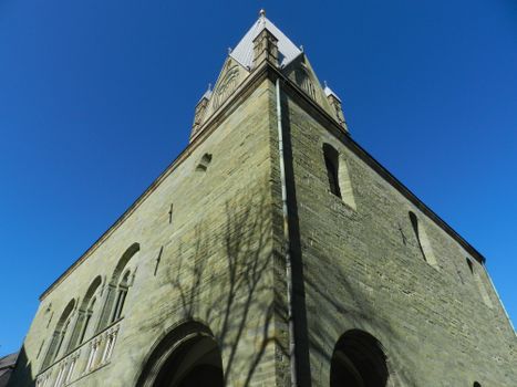 Low-angle view of historic church tower against clear blue sky in Soest, Germany.
